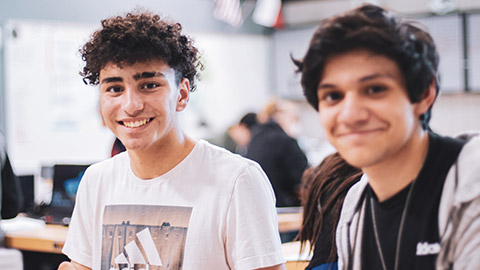 2 youths smiling and enjoying an activity in an indoor environment