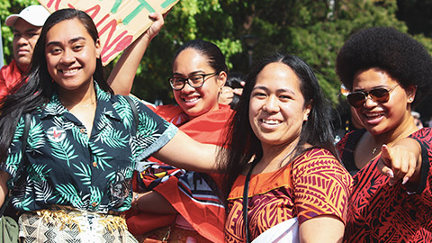 A group of young Pasifika women smiling and laughing outdoors