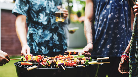 A group of friends standing around an outdoor barbeque