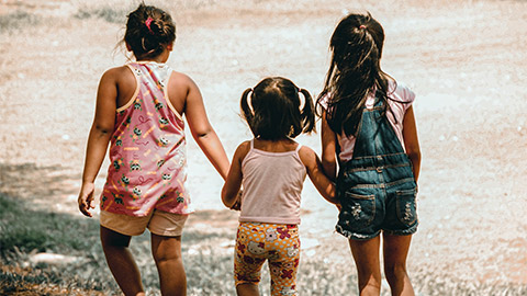 Three children walking through the park in the afternoon