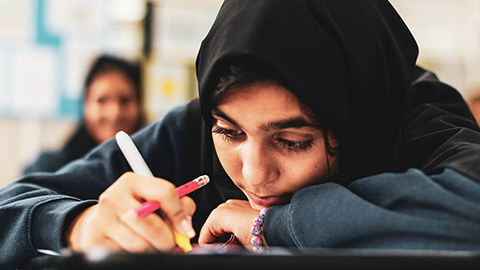 A young muslim girl working on a project in a school environment