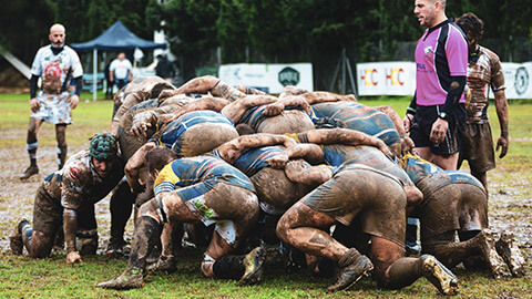 Two rugby teams packing a scrum in the mud