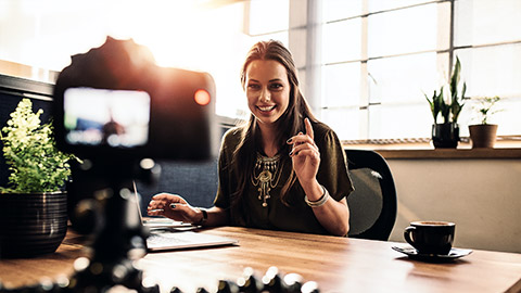 Young woman recording video for her vlog on a digital camera mounted on flexible tripod