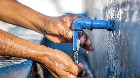 Man's hand on water faucet