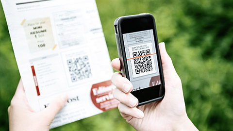 Hand scanning QR code from newspaper