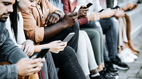 students sitting on row, using smartphones