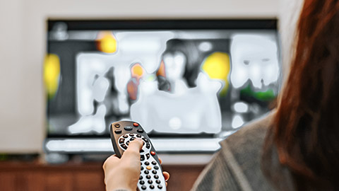 Woman holding remote control, watching television