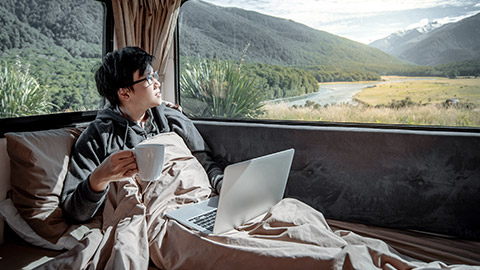 Young man on camper van looking at the scenery