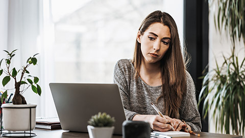 Woman writing notes looking skeptical