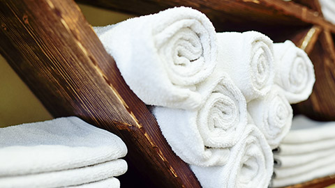 white clean towels neatly folded on a wooden shelf