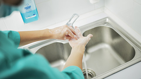 doctor in protective mask washes hands thoroughly