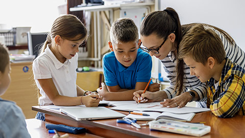 teacher helps school kids to finish they lesson