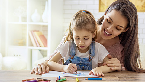 Adult woman guides the child how to draw