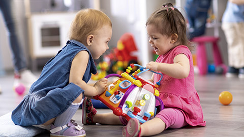 Two kids fighting over a toy in kindergarten or nursery