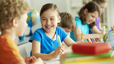 happy pupil looking at her classmate at lesson