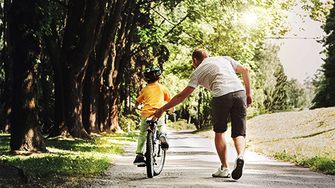 a father and child teaching how to ride a bike