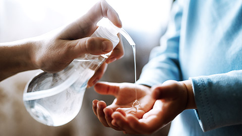 A child holding out hand to recieve acohol gel from educator