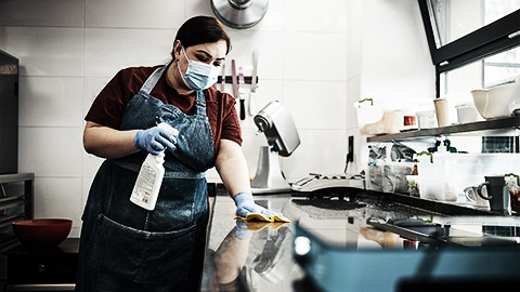 A person cleaning kitchen surfaces