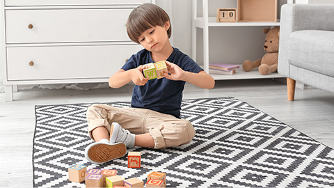 Little boy with autistic disorder playing with cubes at home