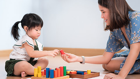 A precious moment of adorable little girl 2 years old, learn by play wooden colorful blocks with her beautiful mother