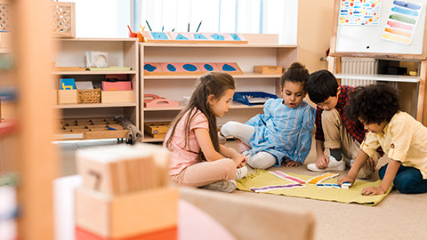 Selective focus of children playing game on floor in montessori school