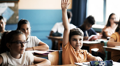 A child raising their hand in a classroom