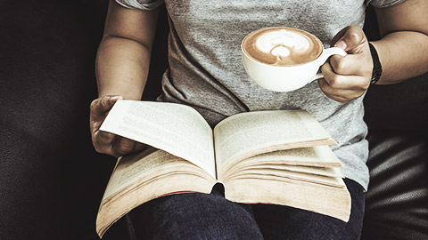 A person reading with a coffee in hand