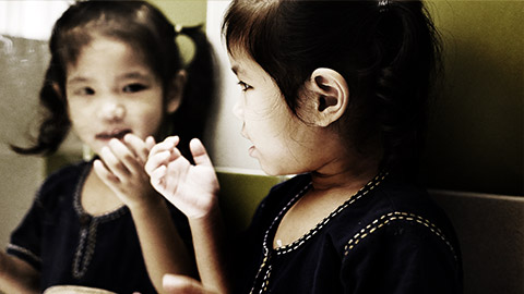 A child looking at herself in the mirror