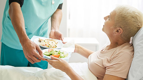 A carer giving food to a patient