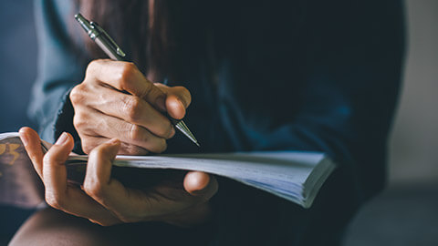 A close view of a worker writing report information into a notebook