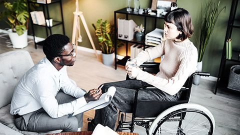 Woman on wheelchair talking with psychotherapist