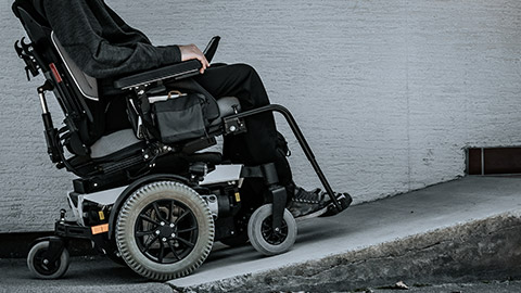 Man on electric wheelchair approaching a ramp