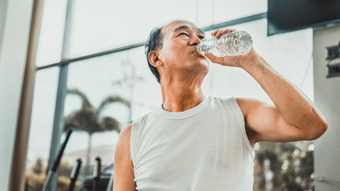 Senior man drink mineral water in gym fitness center after exercise