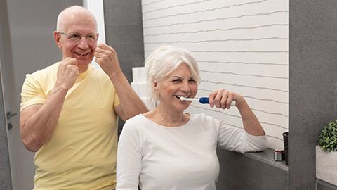 Elderly people using brushing teeth and dental floss. Morning in the bathroom