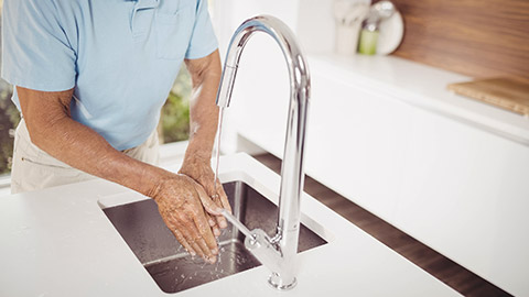 Mid section of senior man washing hands in the kitchen