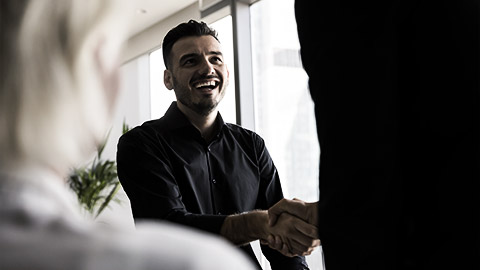 Two people agreeing shaking hands at a gathering