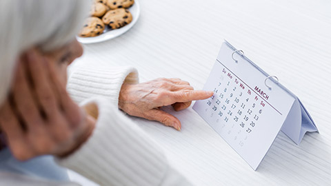 an elderly woman pointing at calendar