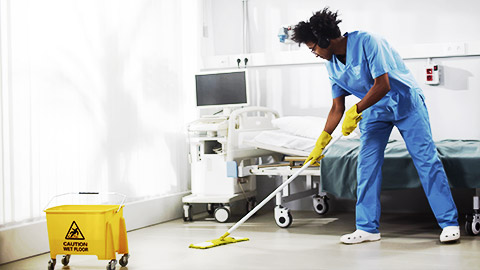 A colleague cleaning a patient's room with a mop