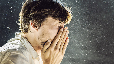 A person covering their mouth while sneezing