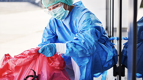 A care professional holding a biohazard trash bag