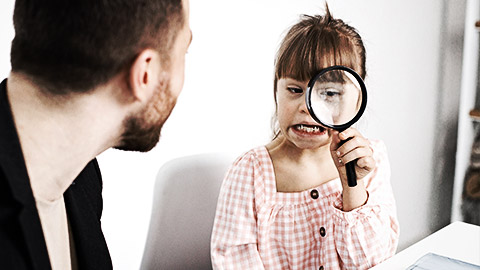 A special needs child holding a magnifying glass