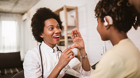 Smiling deaf african american girl with ear implant at doctor's office.