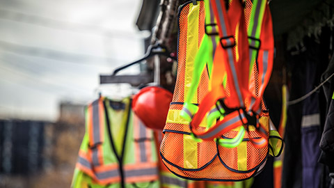 Hi-vis vests and helmets hanging at a worksite