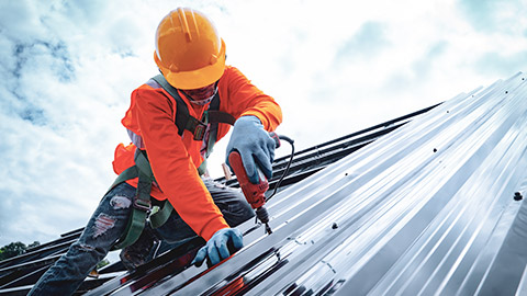 A roofing contractor on the roof wearing safety gear