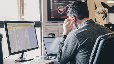 A construction manager sitting at a desk looking at project information on multiple monitors