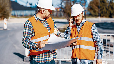 Two workers discussing plans on a building site