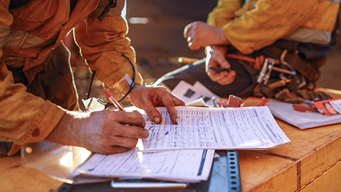 A close view of a construction supervisor filling out paperwork on a work site