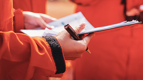 A close view of a female worksite supervisor discussing safety review findings with colleagues