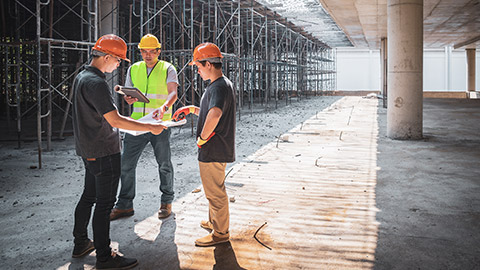 Three workers on a construction site discussing a plan