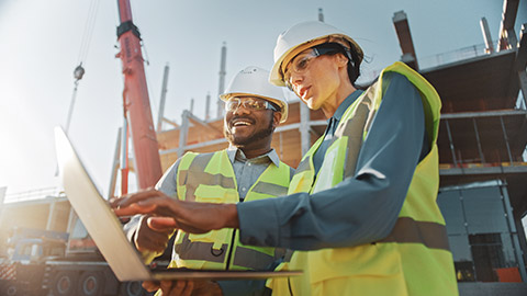 Coworkers on a work site absorbing data on a laptop